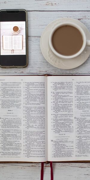 Tablescape of an open Bible, smart phone and hot drink